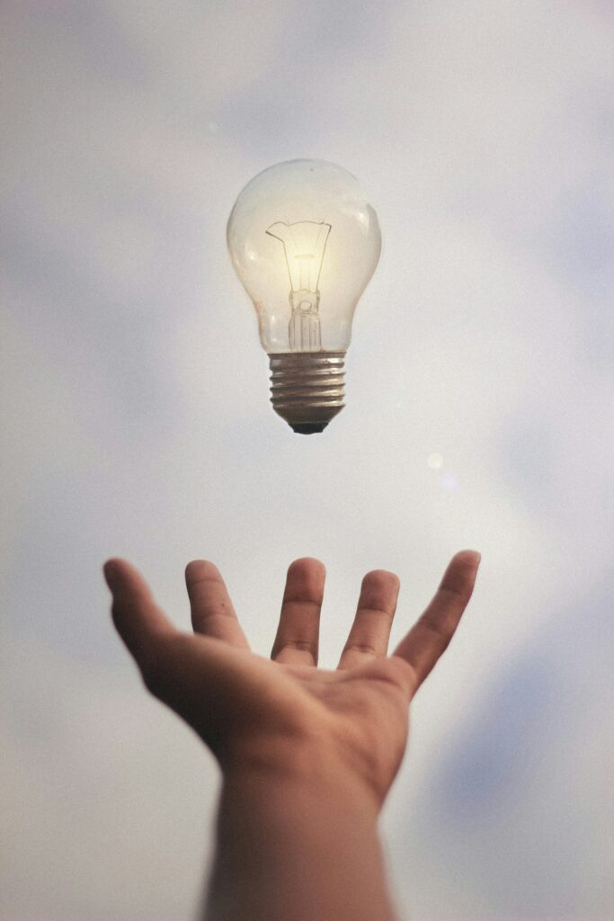 Image that shows a human hand throwing a light bulb in the air.